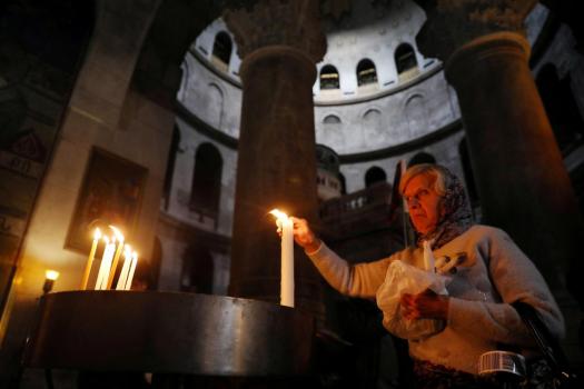 FILE PHOTO: A worshipper lights a candle as she visits the Church of the Holy Sepulchre in Jerusalem's Old City